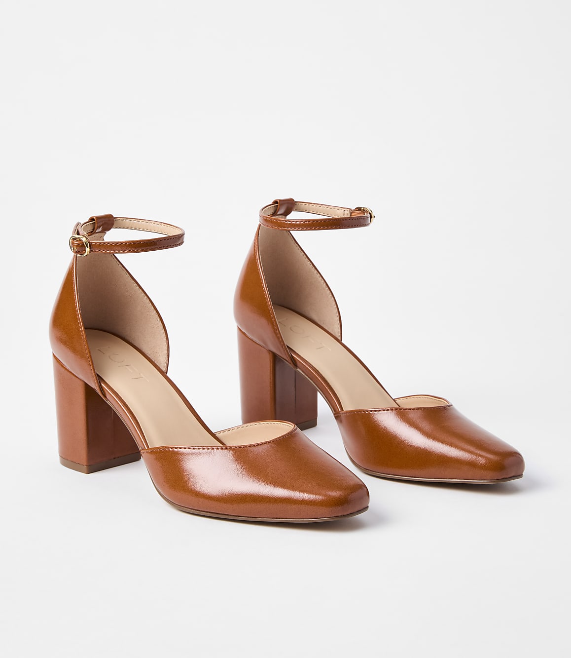 A pair of glossy brown leather ankle strap heels with block heels are displayed against a plain white background.