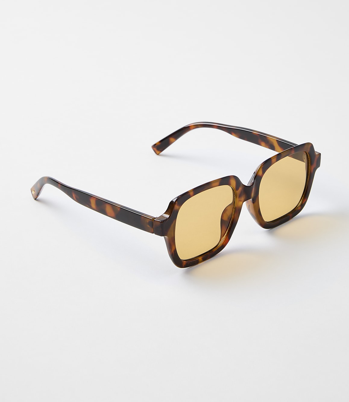 Tortoiseshell sunglasses with amber lenses rest on a plain white background.