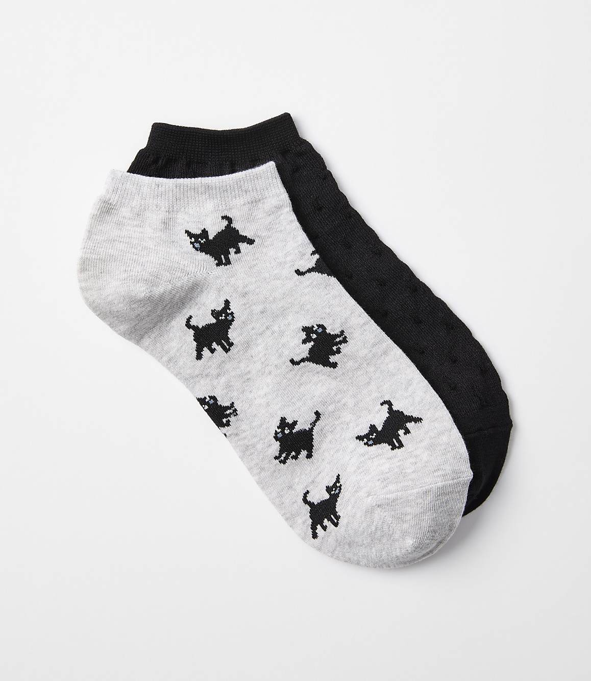 A pair of ankle socks, one light gray with black cat patterns and the other black with a textured pattern, lie on a white background.