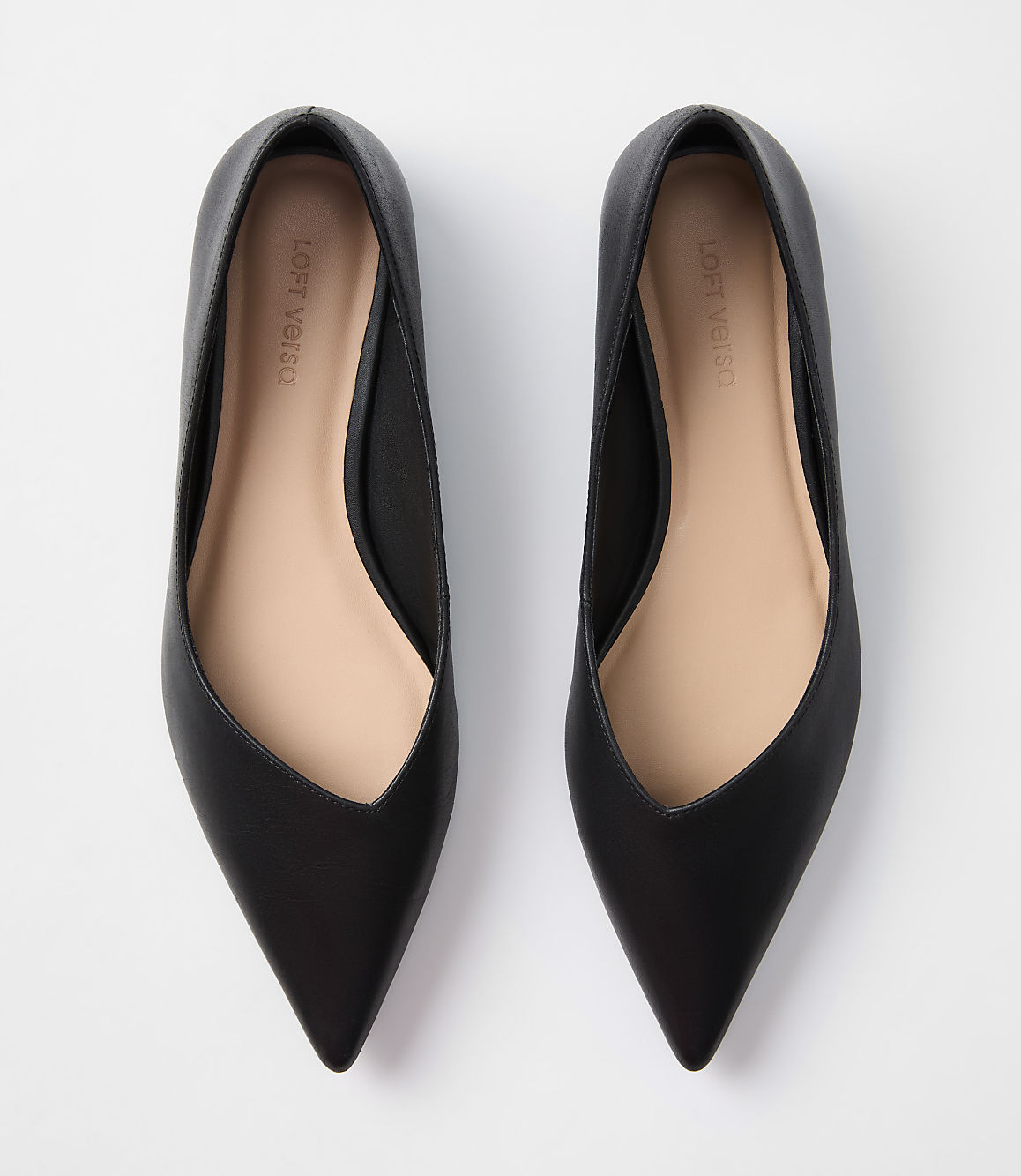 A pair of black pointed-toe flats rests on a plain white background.