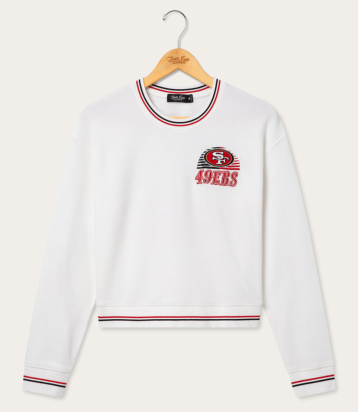 A white San Francisco 49ers sweatshirt with striped cuffs and neckline hangs on a wooden hanger against a plain white background.