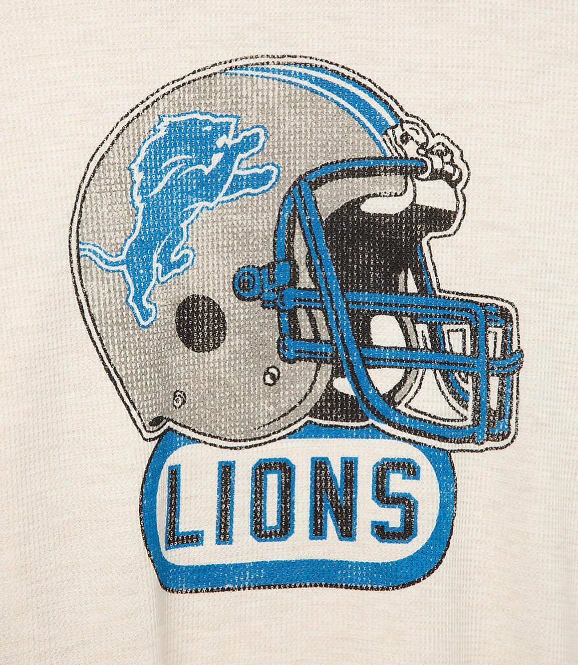 A Detroit Lions helmet logo with the word "LIONS" below it is centered on a cream-colored textured background.