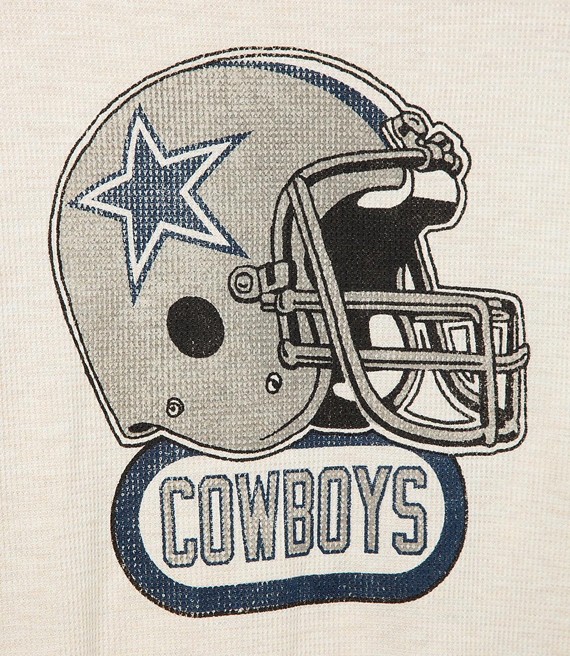 A Dallas Cowboys helmet with the team name below is centered on a textured, light-colored background.