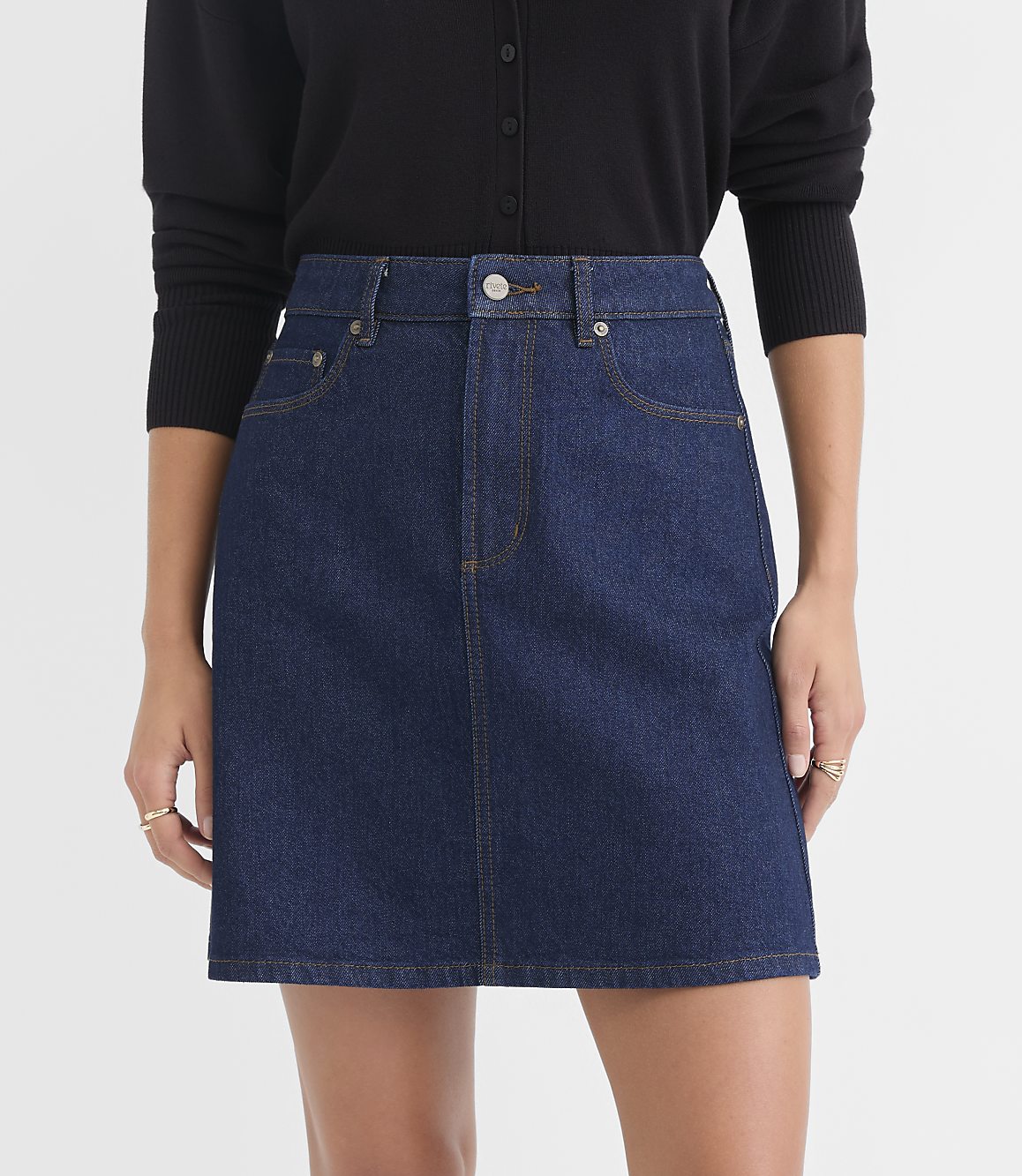 A dark wash denim skirt with a black cardigan is presented against a plain white background.
