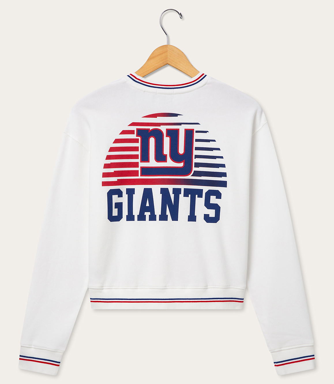 A white sweatshirt with a New York Giants logo on the back is hanging on a wooden hanger against a plain white background.