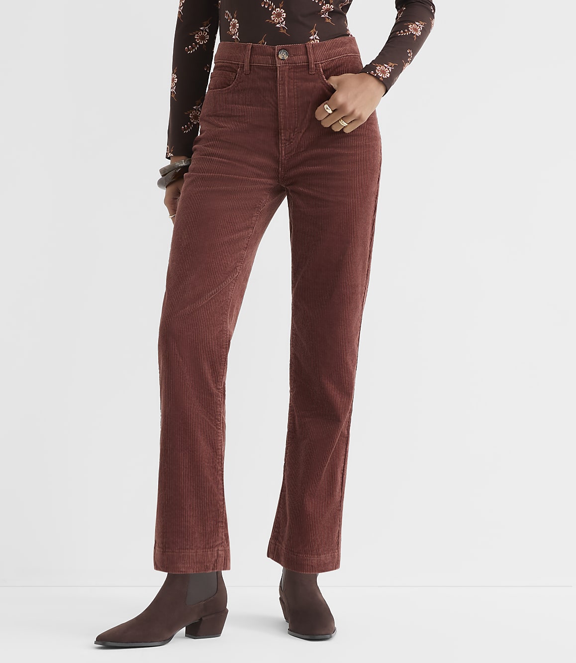 A person stands in rust-colored corduroy pants and brown boots against a plain white background.