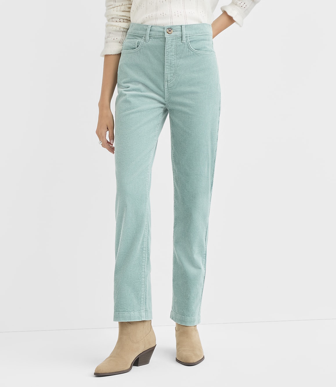 A person stands wearing light blue corduroy pants and tan boots against a plain white background.