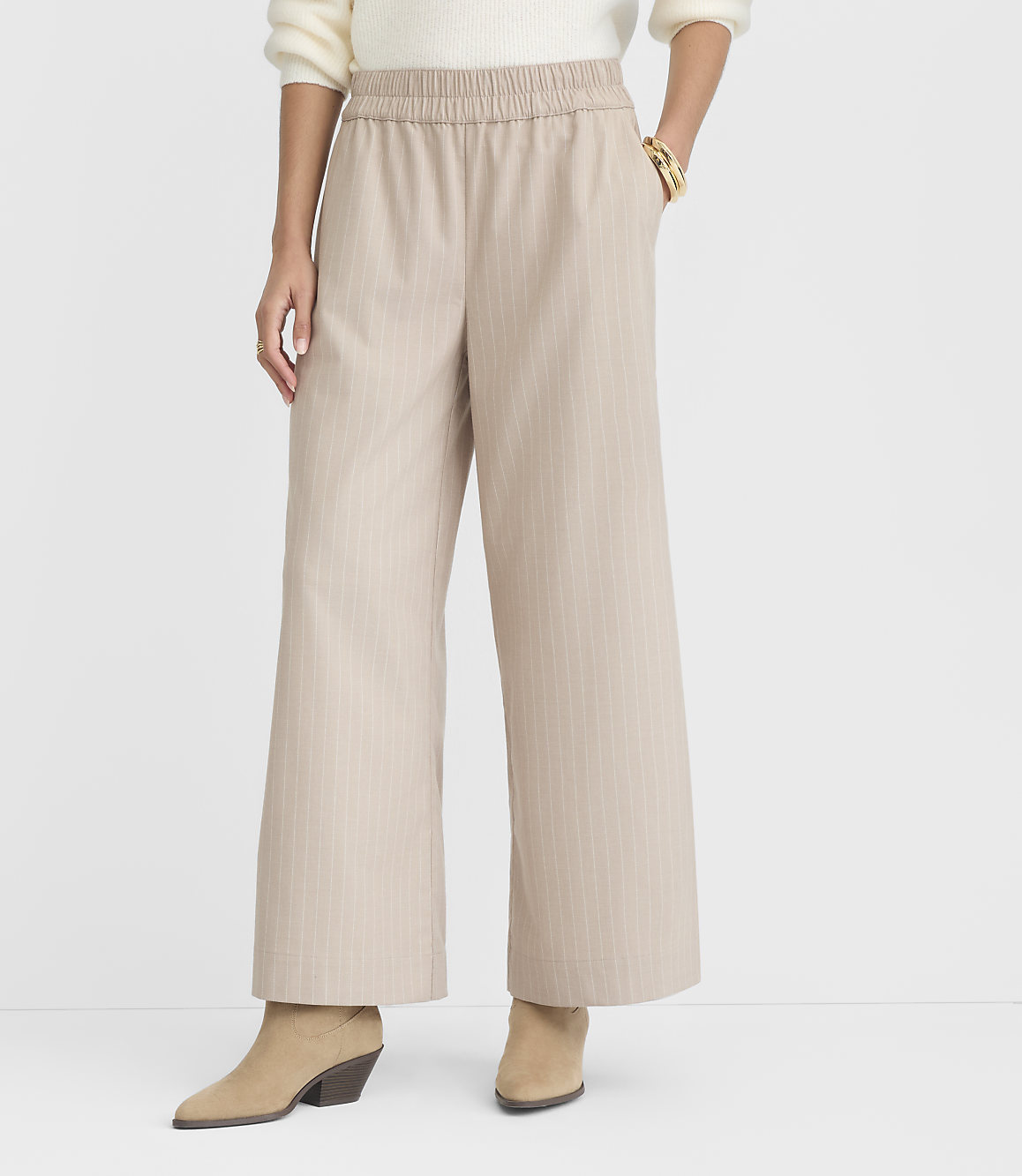 A person stands in beige pinstripe wide-leg pants and tan ankle boots against a plain white background.