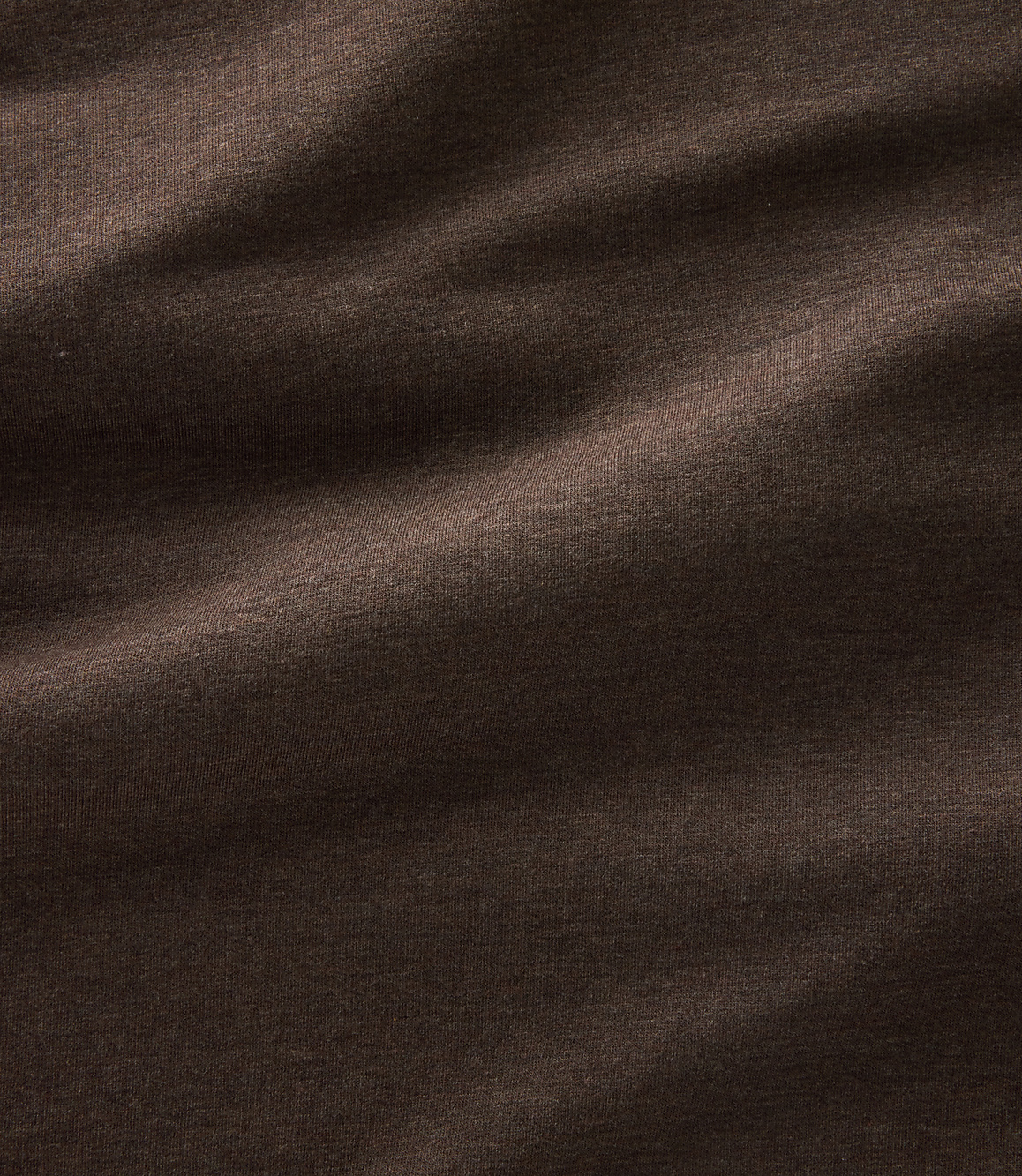 Dark brown fabric with soft folds and subtle highlights creates a textured background.