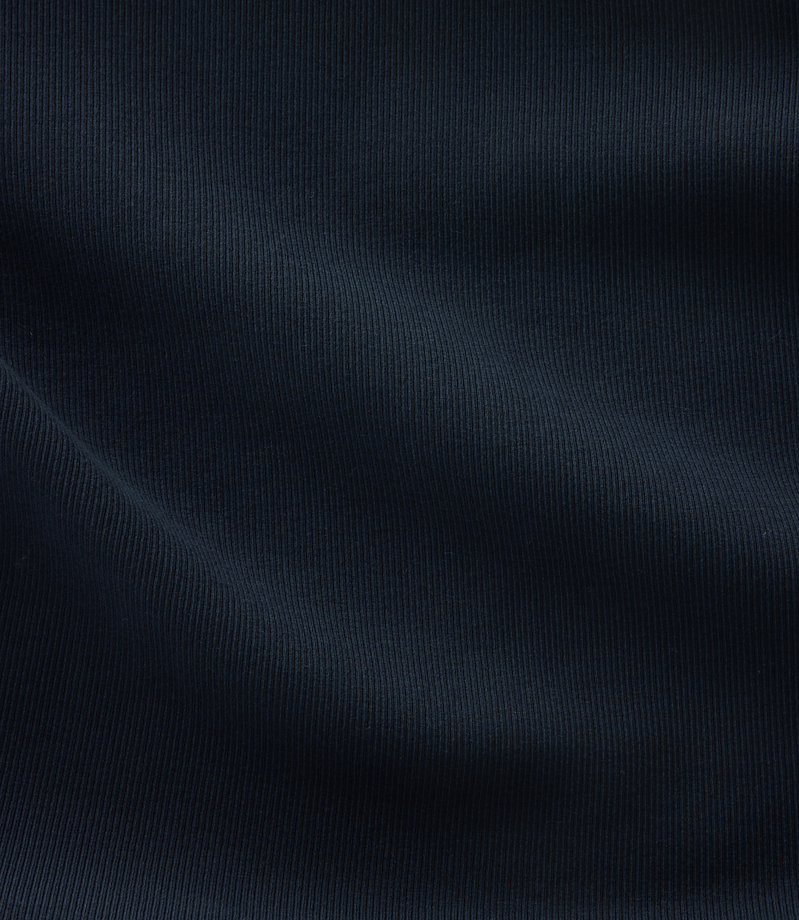 A dark blue, ribbed fabric with soft folds fills the frame, creating a textured and shadowed surface.