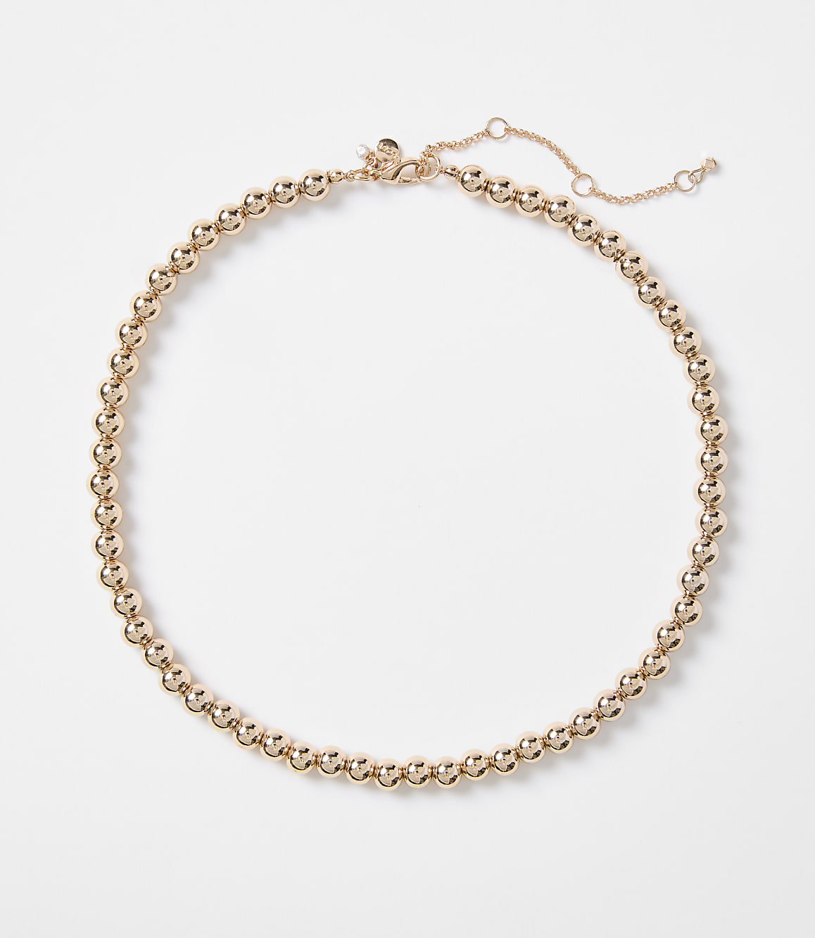 A rose gold beaded necklace with a delicate chain closure rests on a plain white background.