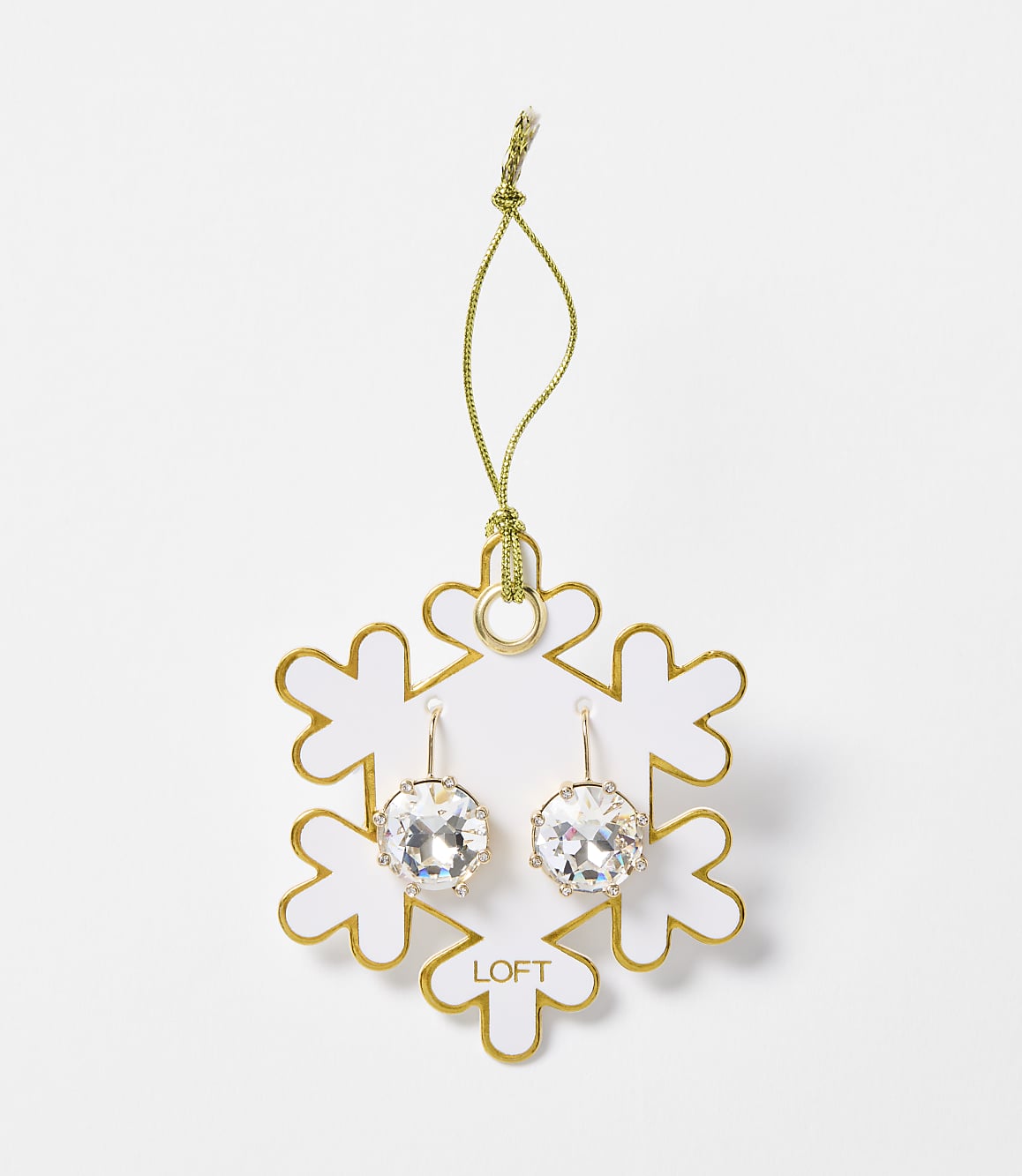 A pair of sparkling crystal earrings hang from a gold string attached to a white snowflake ornament with gold trim, set against a plain white background.