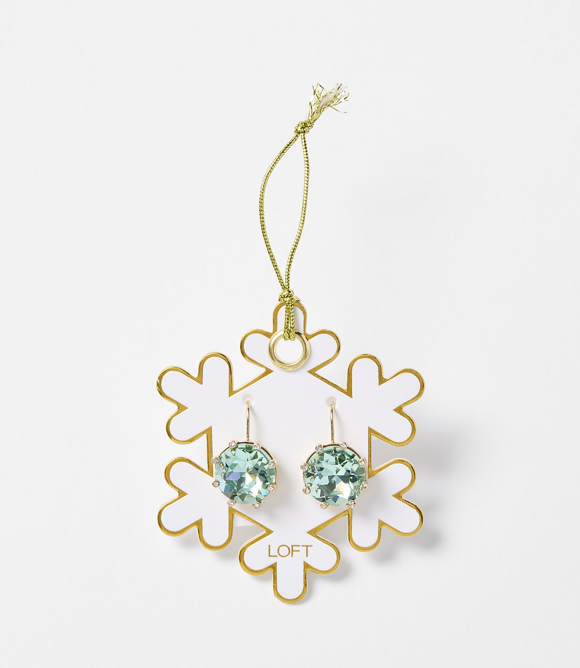 A pair of light blue crystal earrings hang from a gold string attached to a white snowflake ornament with gold trim, set against a plain white background.