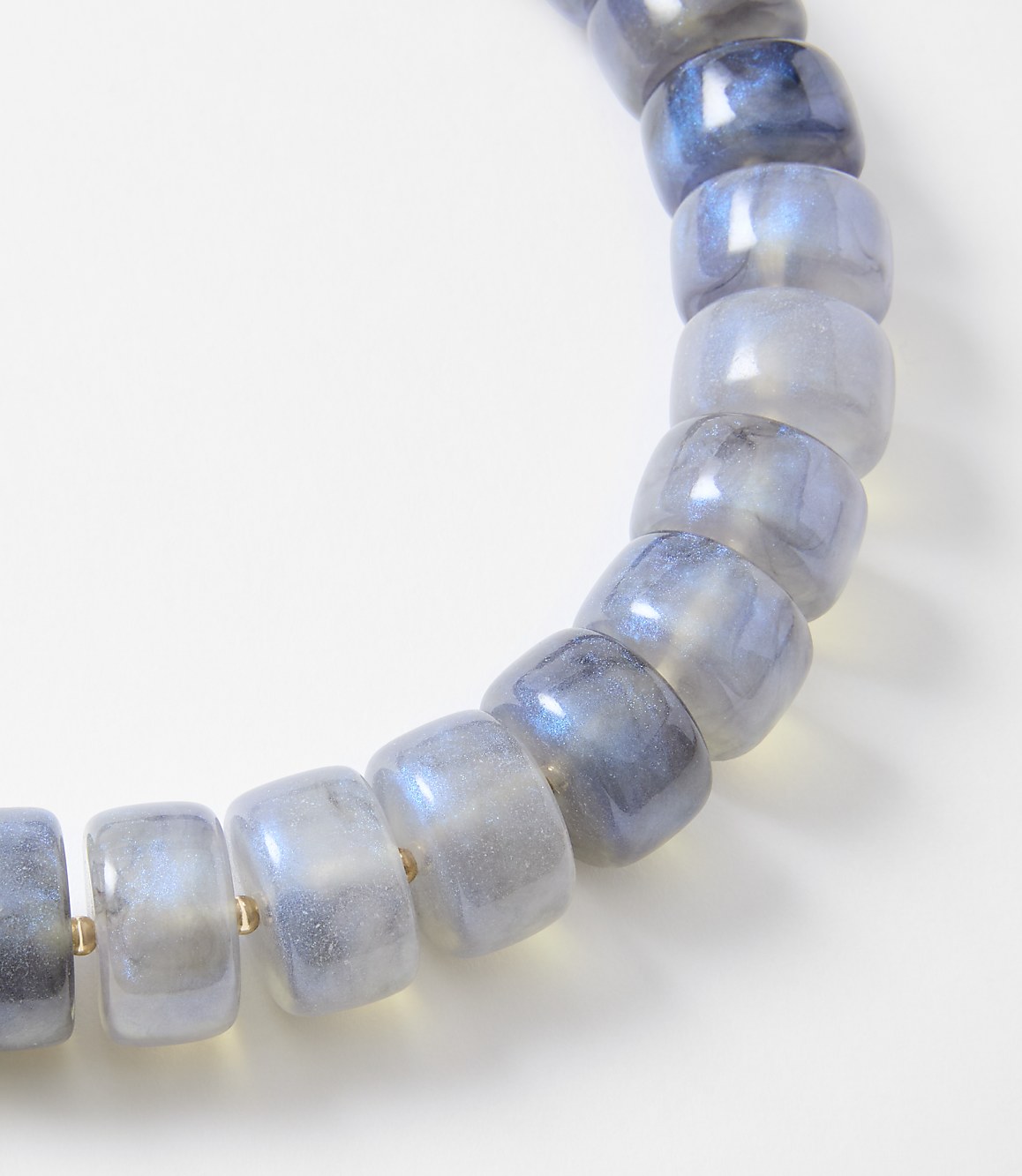 A bracelet of translucent, blue-grey beads with iridescent flashes is displayed against a plain white background.