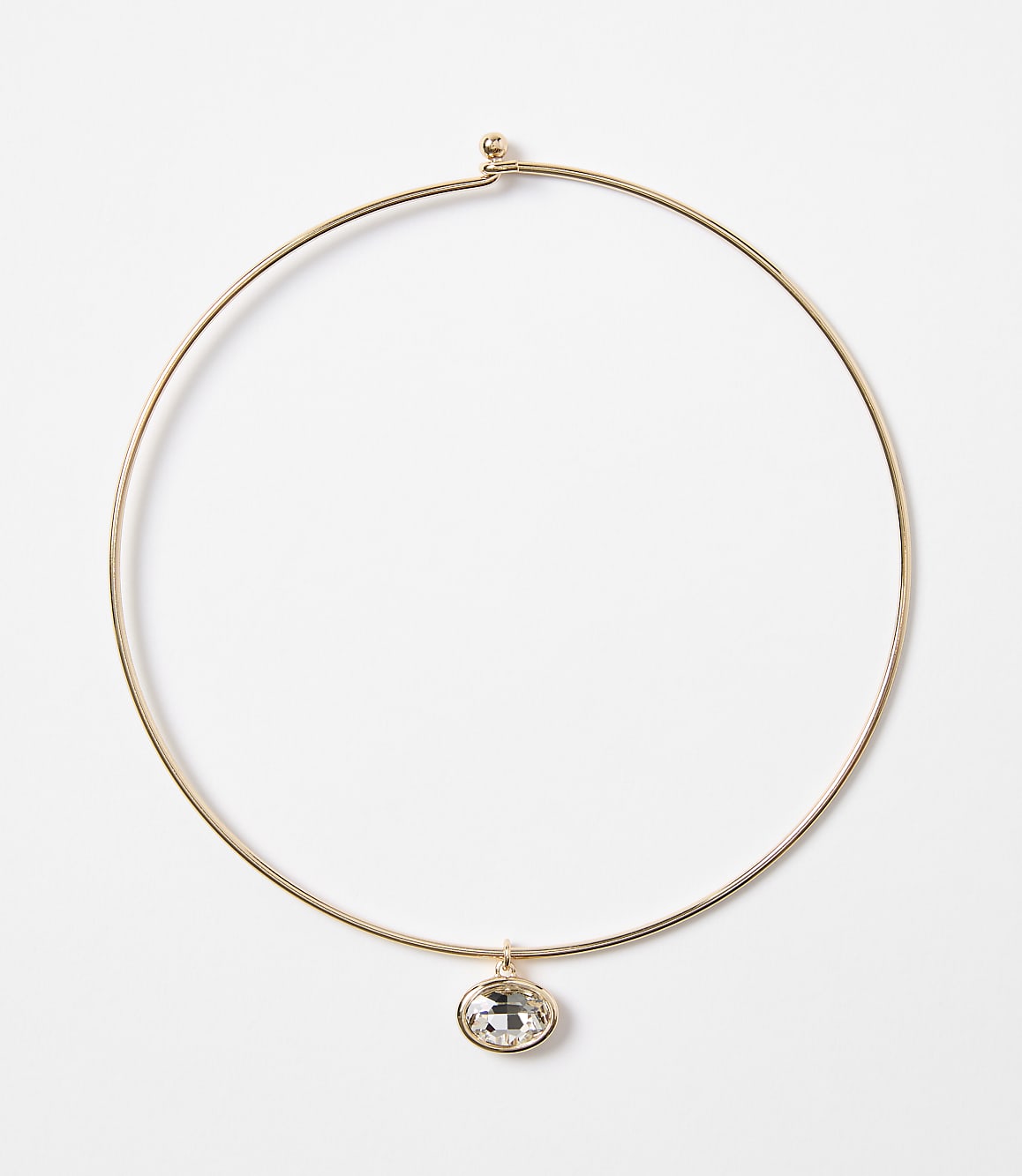 A delicate gold choker necklace with a single oval crystal pendant hangs against a plain white background.