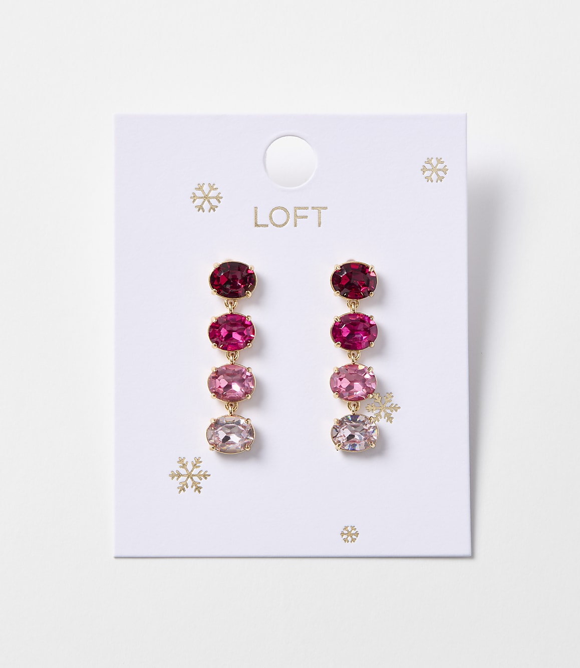 A pair of oval gemstone drop earrings in shades of pink and red hang from a white card with snowflake accents.