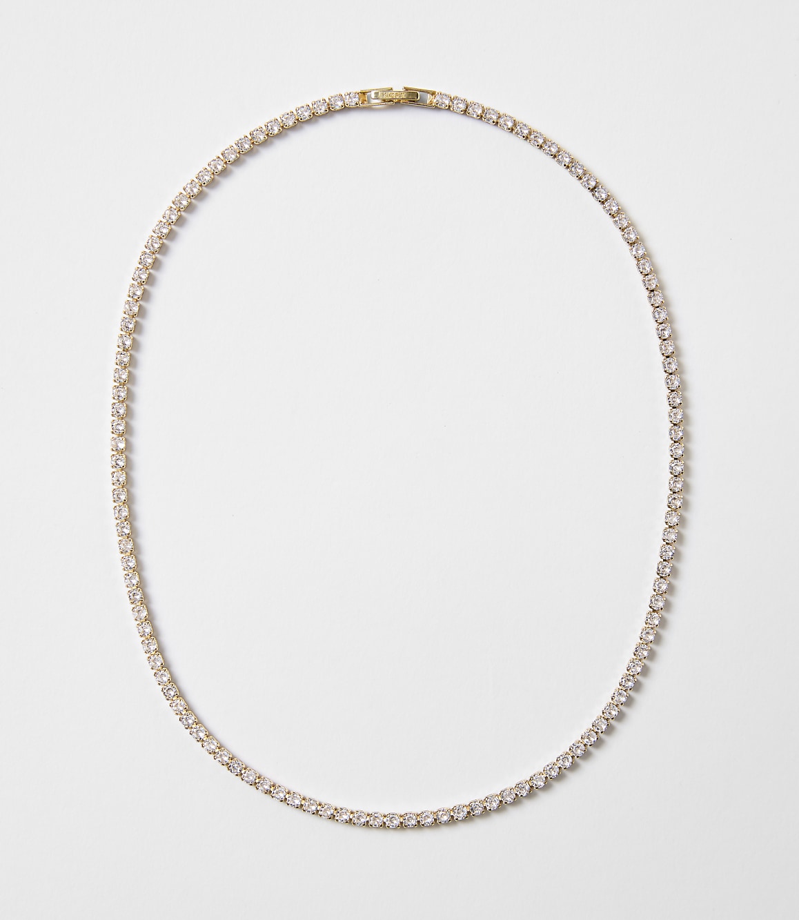 A delicate gold chain necklace with clear stones is laid out on a plain white background.