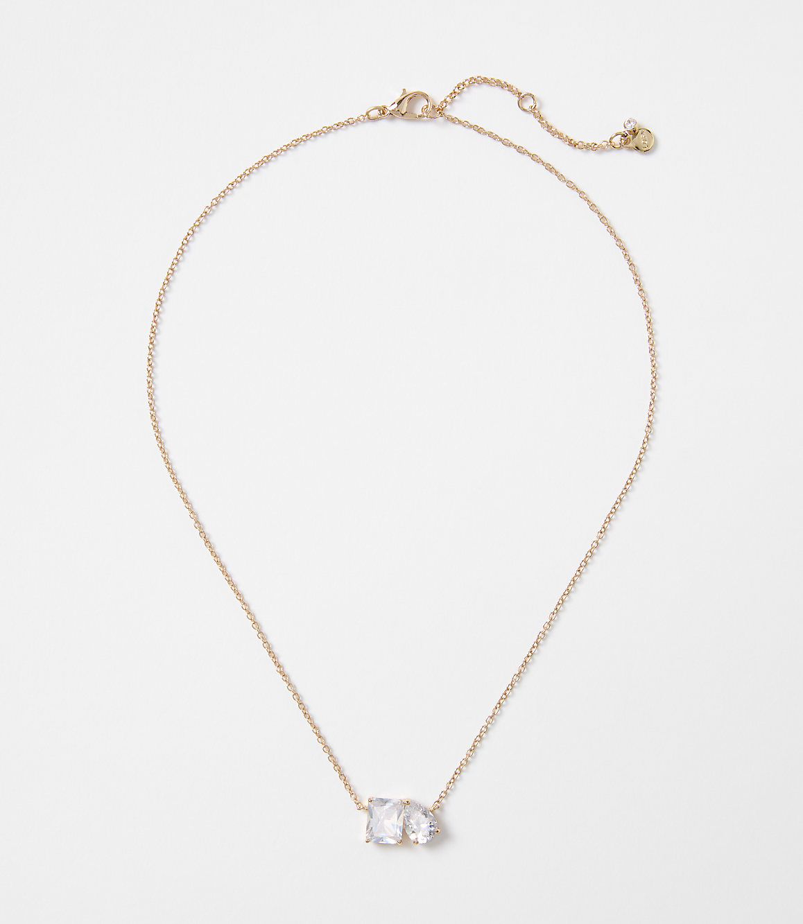 A delicate rose gold necklace with two clear, rectangular stones rests on a plain white background.