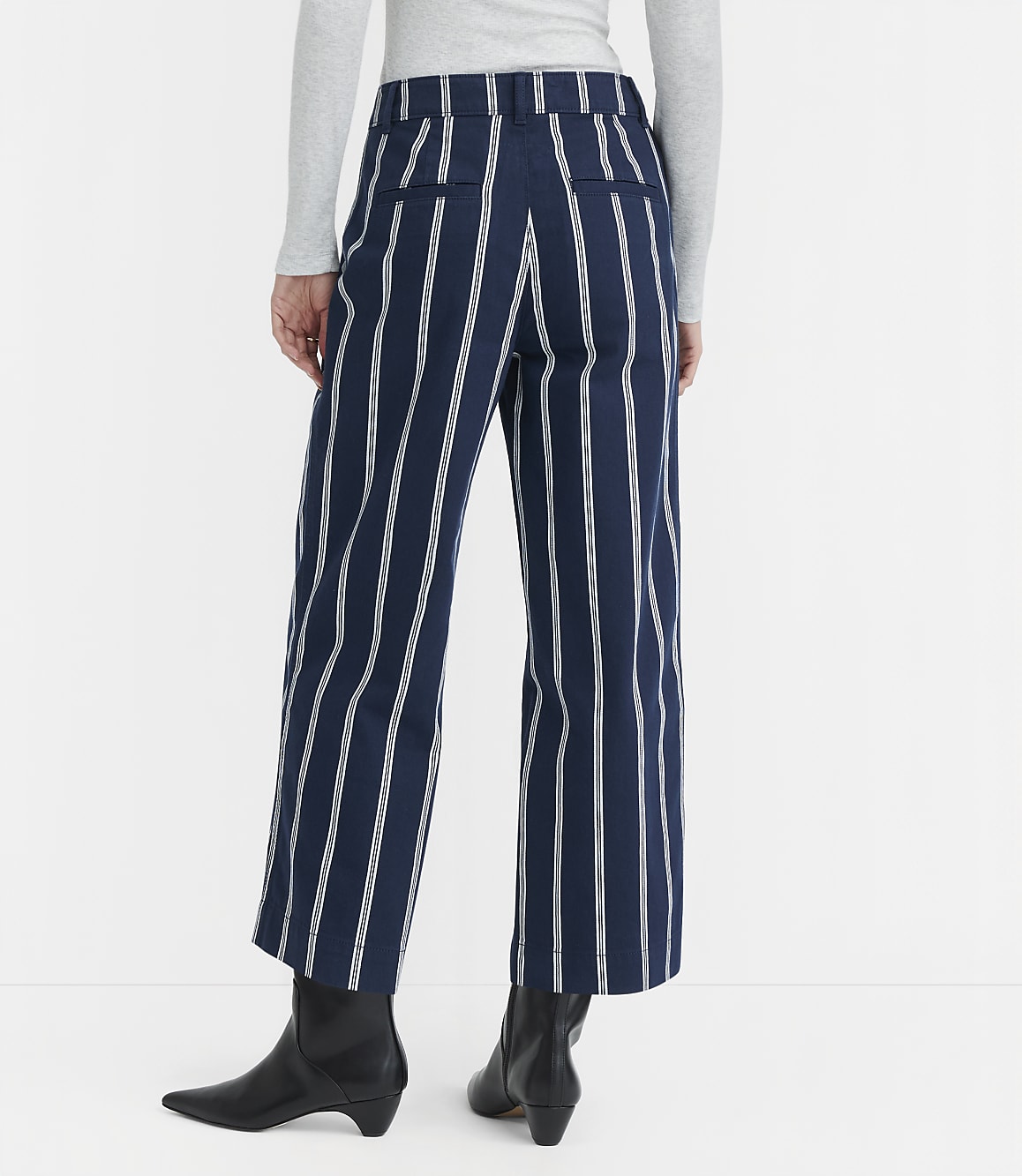 A person wearing navy and white striped culottes and black boots stands against a plain white background.