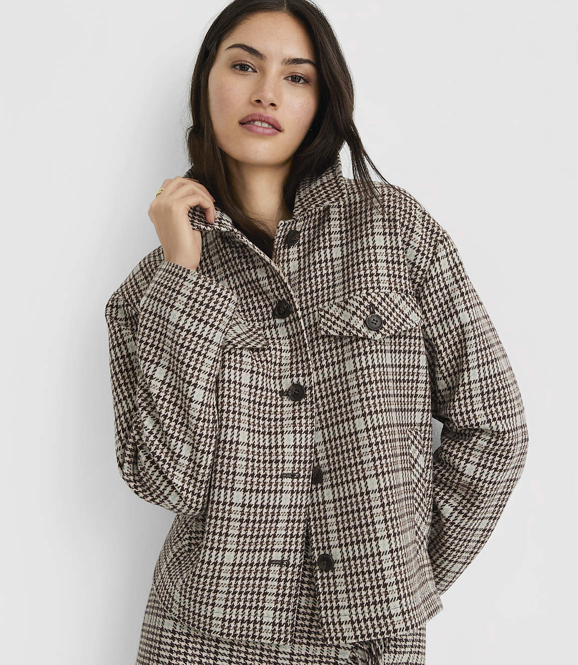 A woman in a plaid jacket stands against a plain white background.