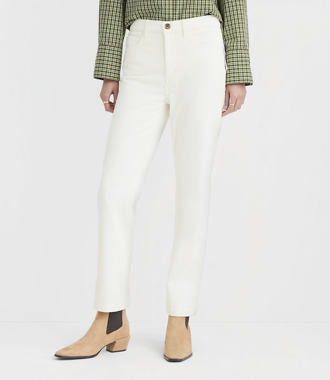 Cream-colored pants and tan ankle boots are featured in the foreground against a plain white background.