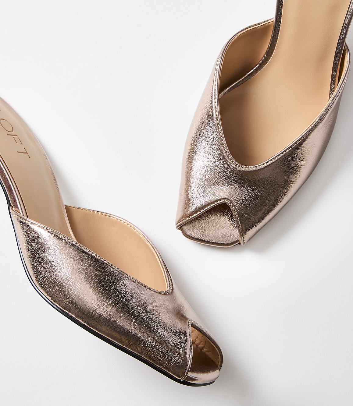 A pair of rose gold peep-toe mules with a pointed toe are displayed against a plain white background.