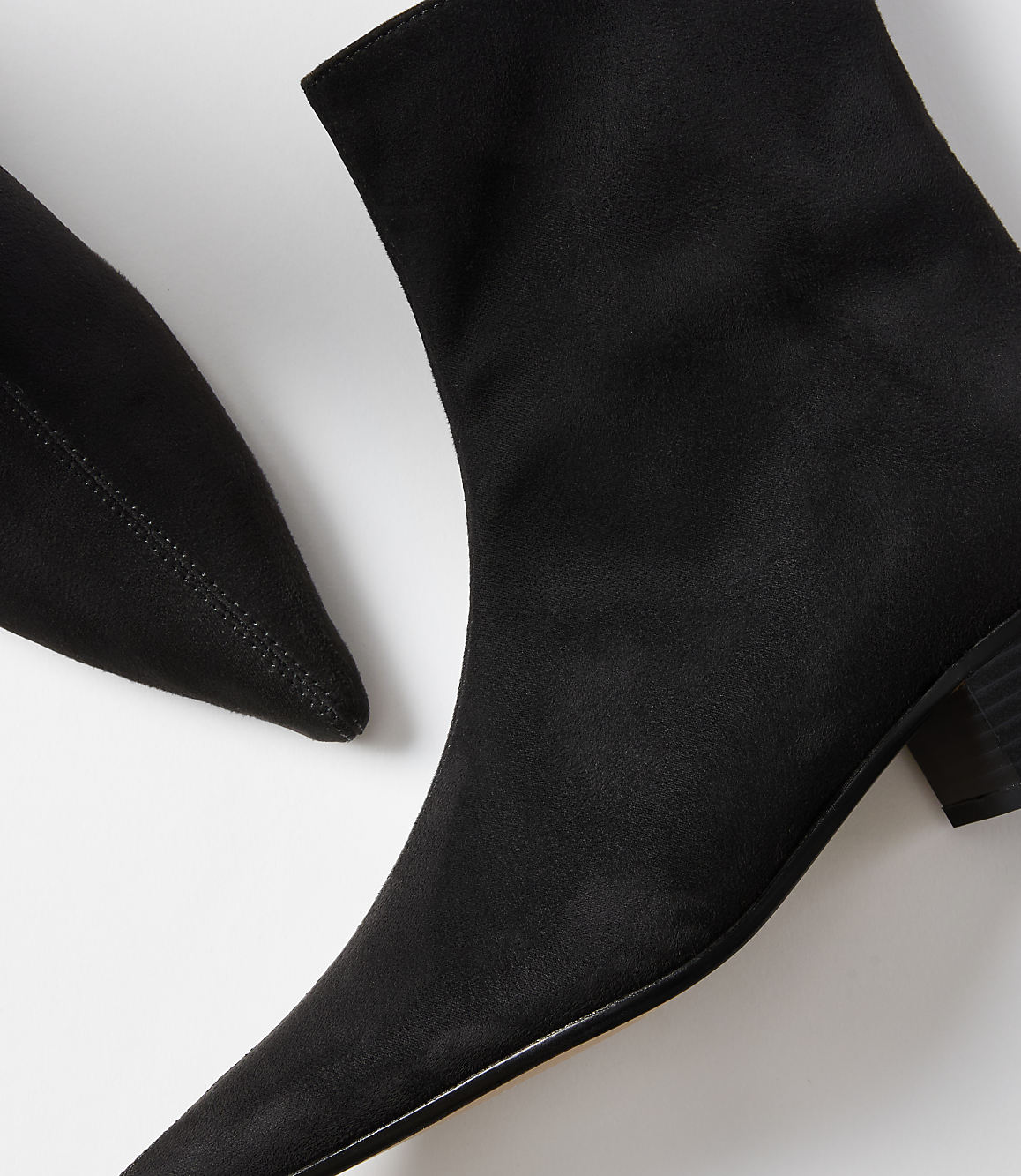A close-up of two black pointed-toe ankle boots with a white background.