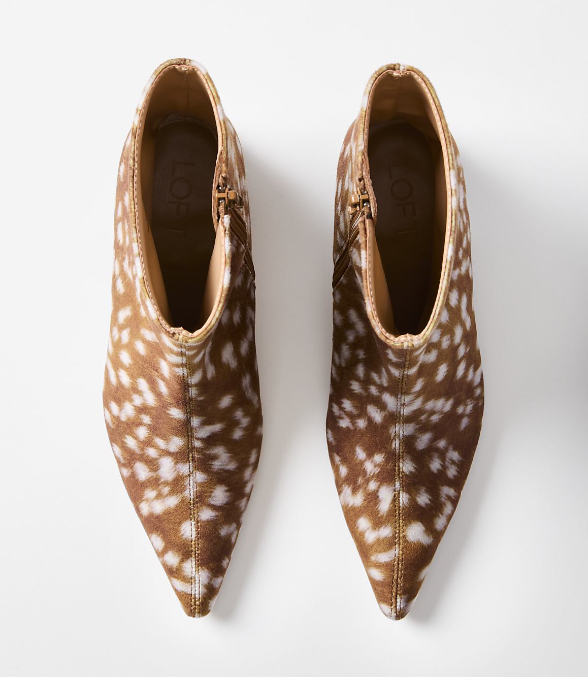 A pair of brown and white spotted ankle boots with pointed toes are displayed against a plain white background.