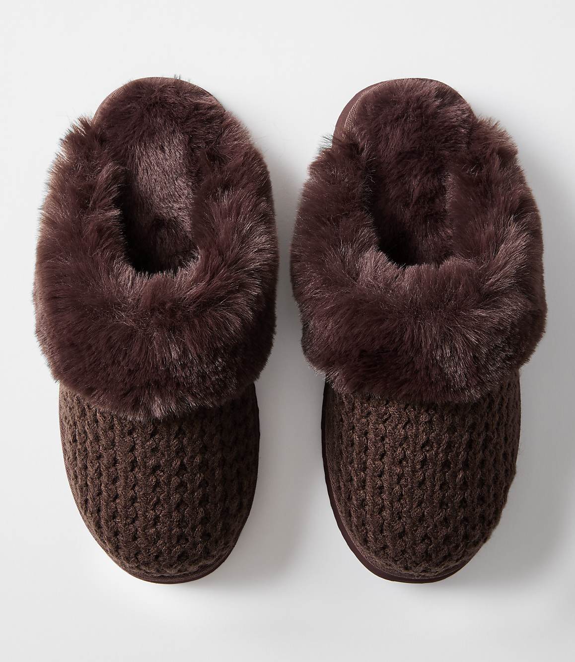 A pair of cozy brown knit slippers with fluffy trim rests on a plain white background.