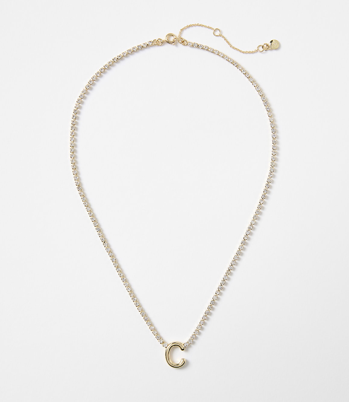 A delicate gold chain with a sparkling pendant in the shape of the letter "C" rests against a plain white background.