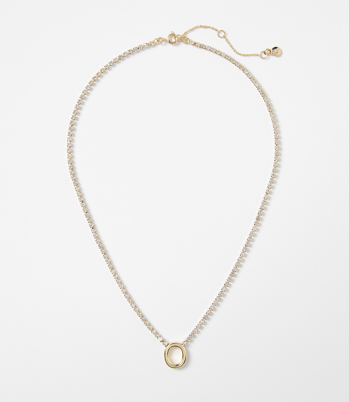 A delicate gold necklace with a circular pendant, adorned with small clear stones, rests against a plain white background.