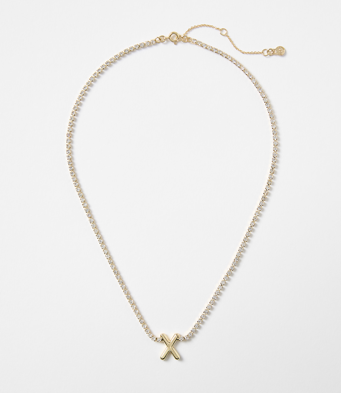 A gold letter "X" pendant on a diamond-encrusted chain rests against a plain white background.