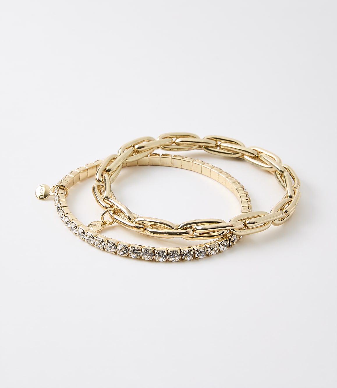 Two gold bracelets, one with a chunky chain design and the other with a band of small rhinestones, rest on a plain white background.