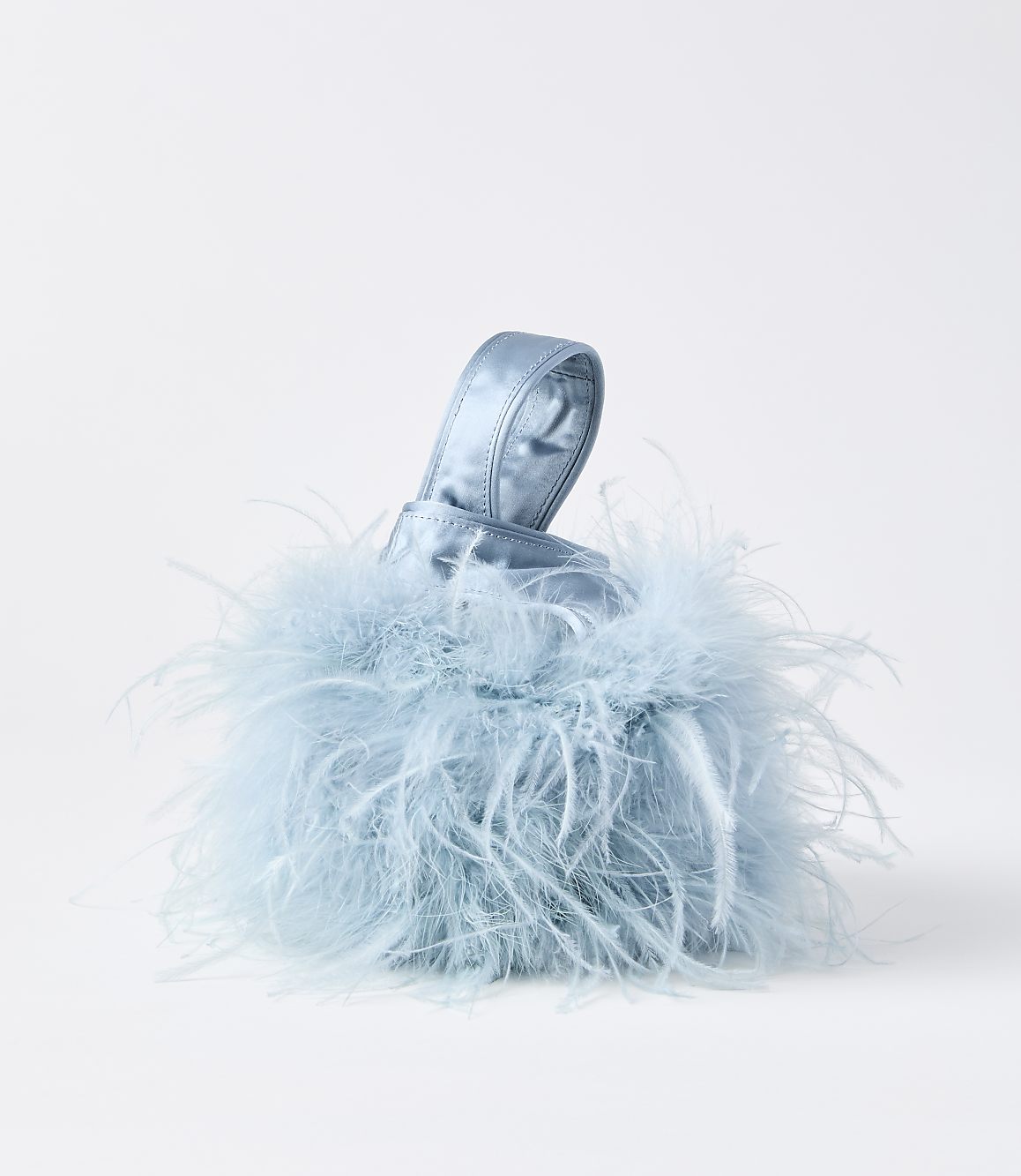 A fluffy, light blue, feather-covered handbag with a satin handle sits against a plain white background.
