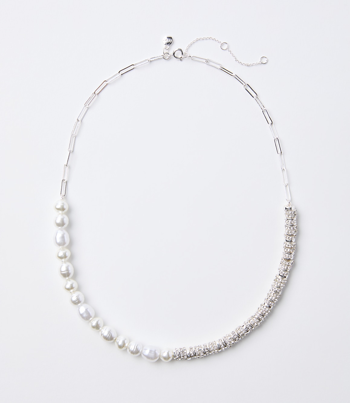 A delicate silver necklace with a chain of pearls on the left and a band of sparkling rhinestones on the right rests on a plain white background.