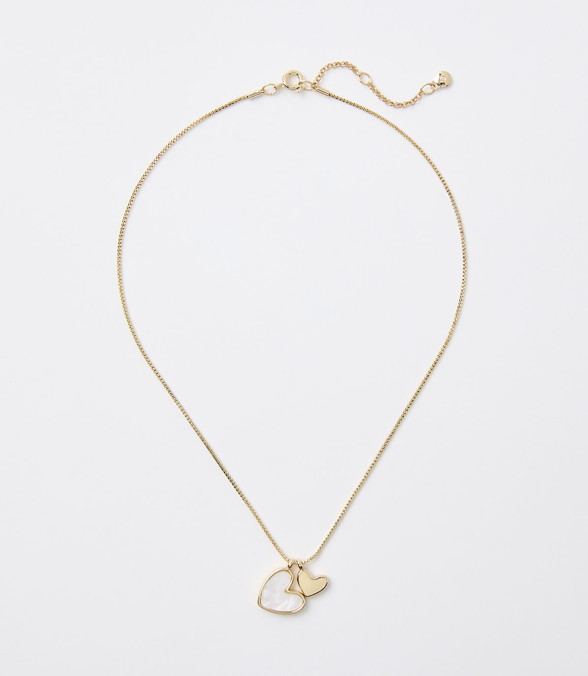 A delicate gold chain necklace with a heart-shaped pearl and a small gold heart charm hangs against a plain white background.