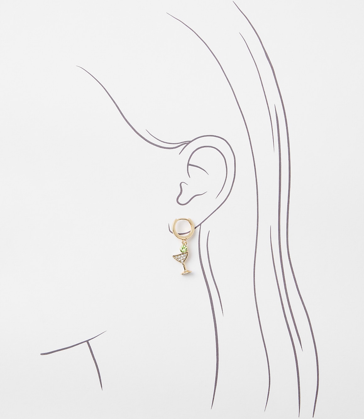 A delicate gold earring shaped like a martini glass with a green gem hangs from a stylized ear against a plain white background.