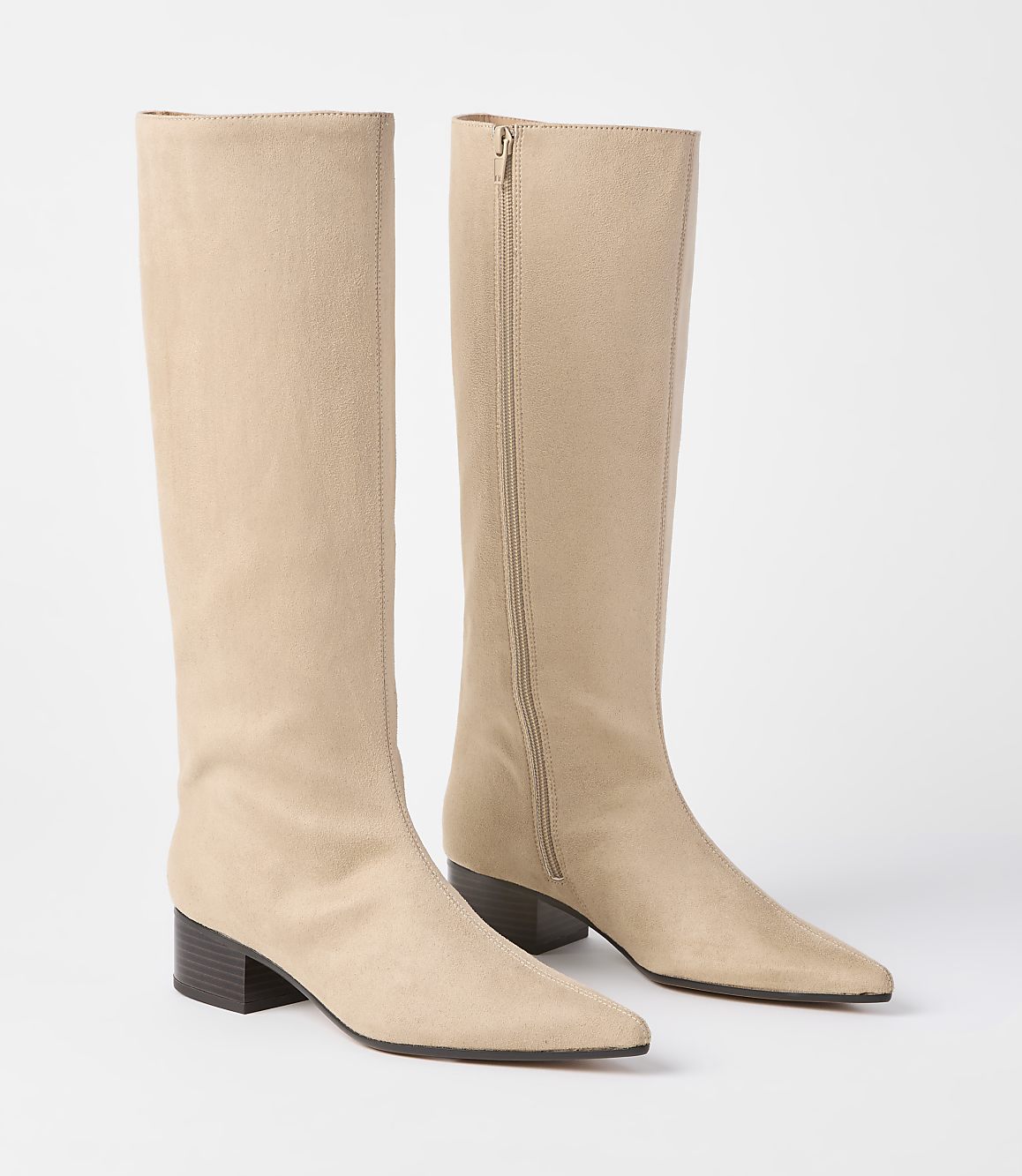 A pair of beige suede knee-high boots with pointed toes and block heels stand on a plain white background.