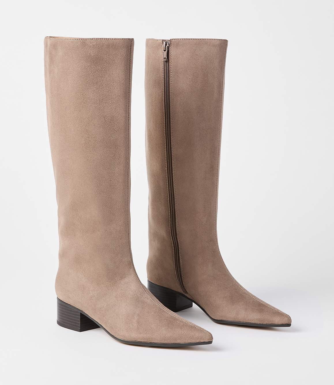 A pair of taupe suede knee-high boots with pointed toes and block heels stand against a plain white background.