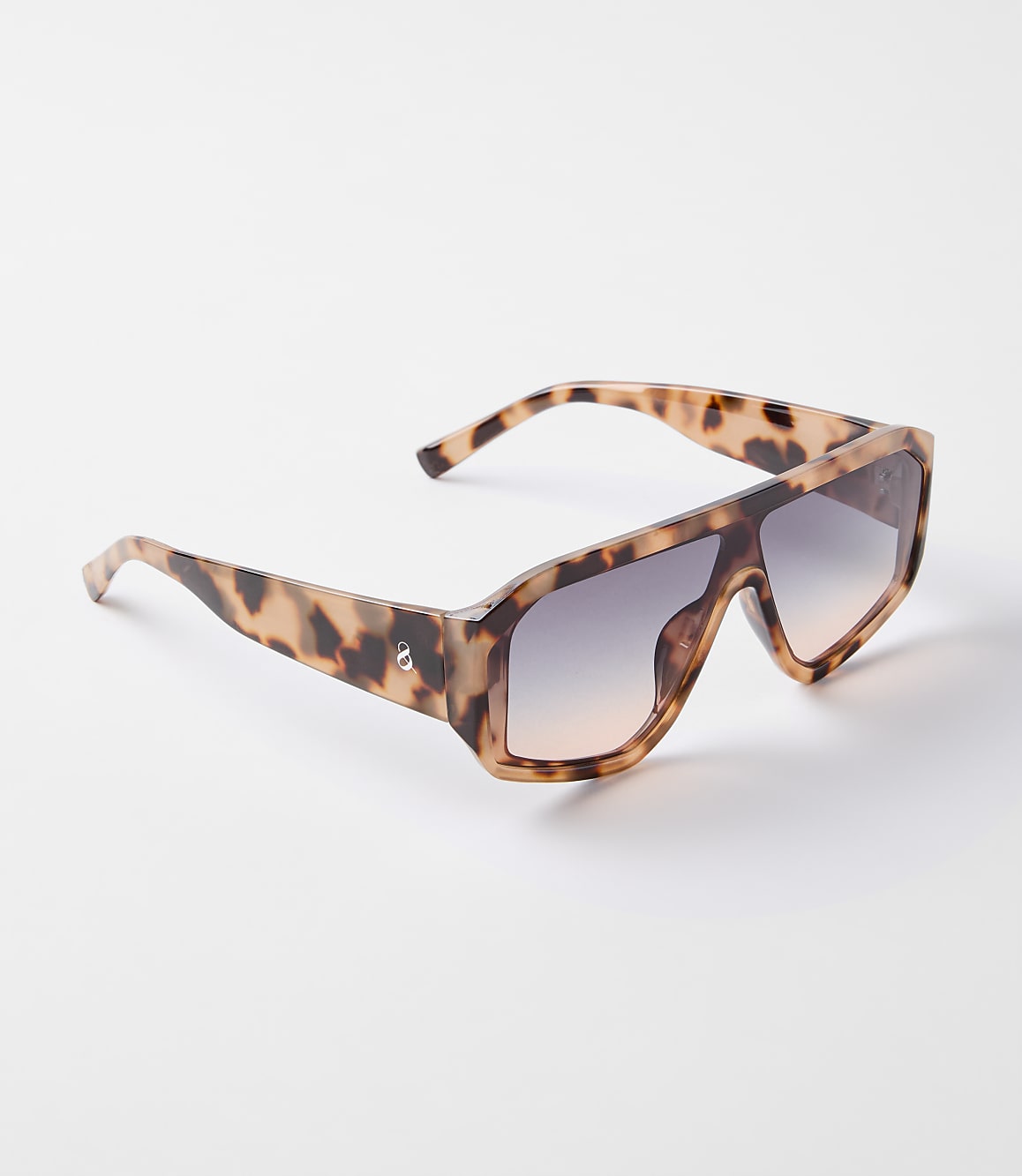A pair of oversized, tortoise-shell sunglasses with gradient lenses rests on a plain white background.
