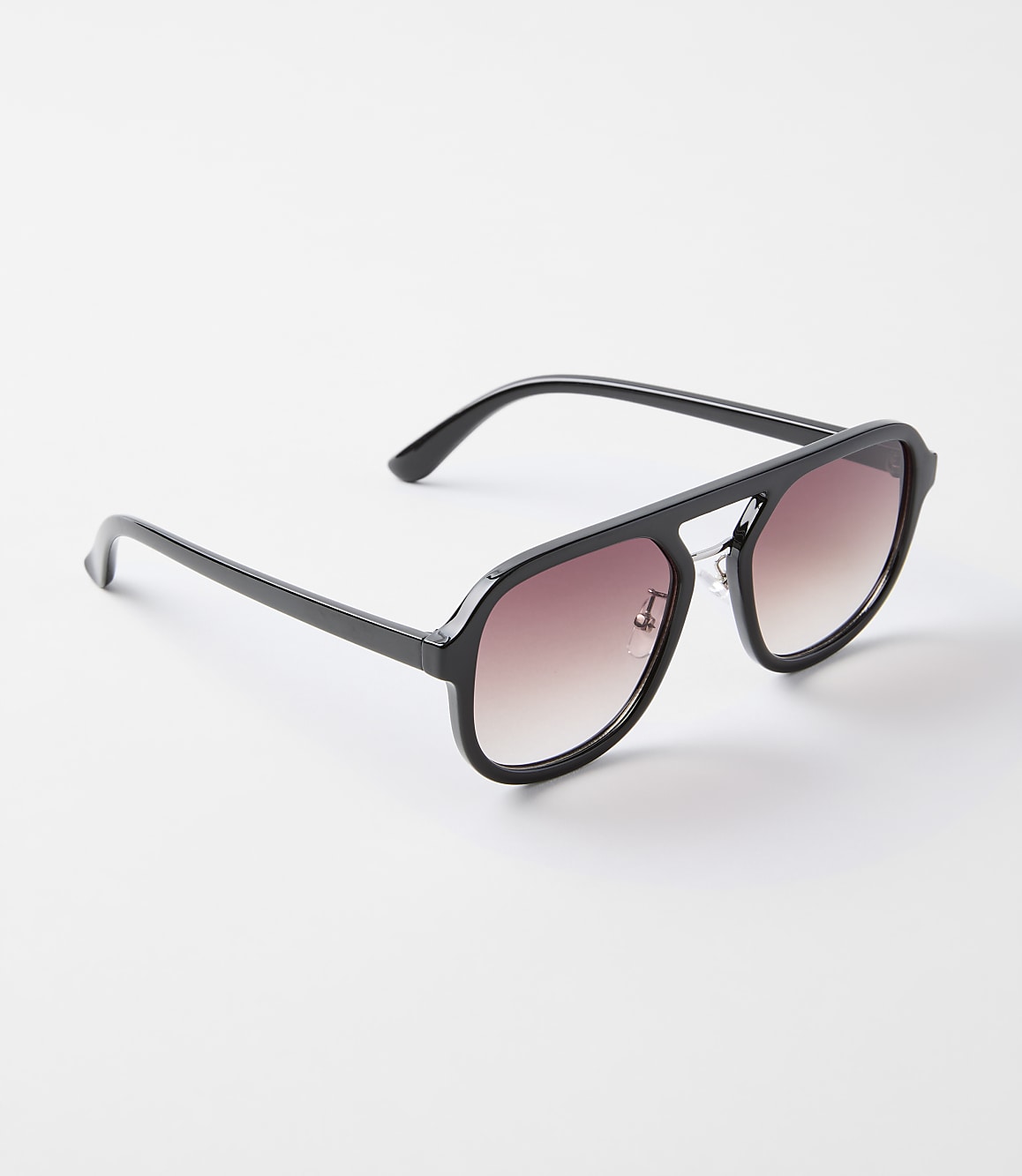 A pair of black aviator sunglasses with gradient lenses rests on a plain white background.