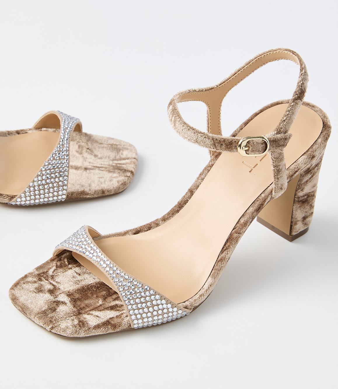 A pair of crushed velvet block heels with rhinestone straps are displayed against a plain white background.