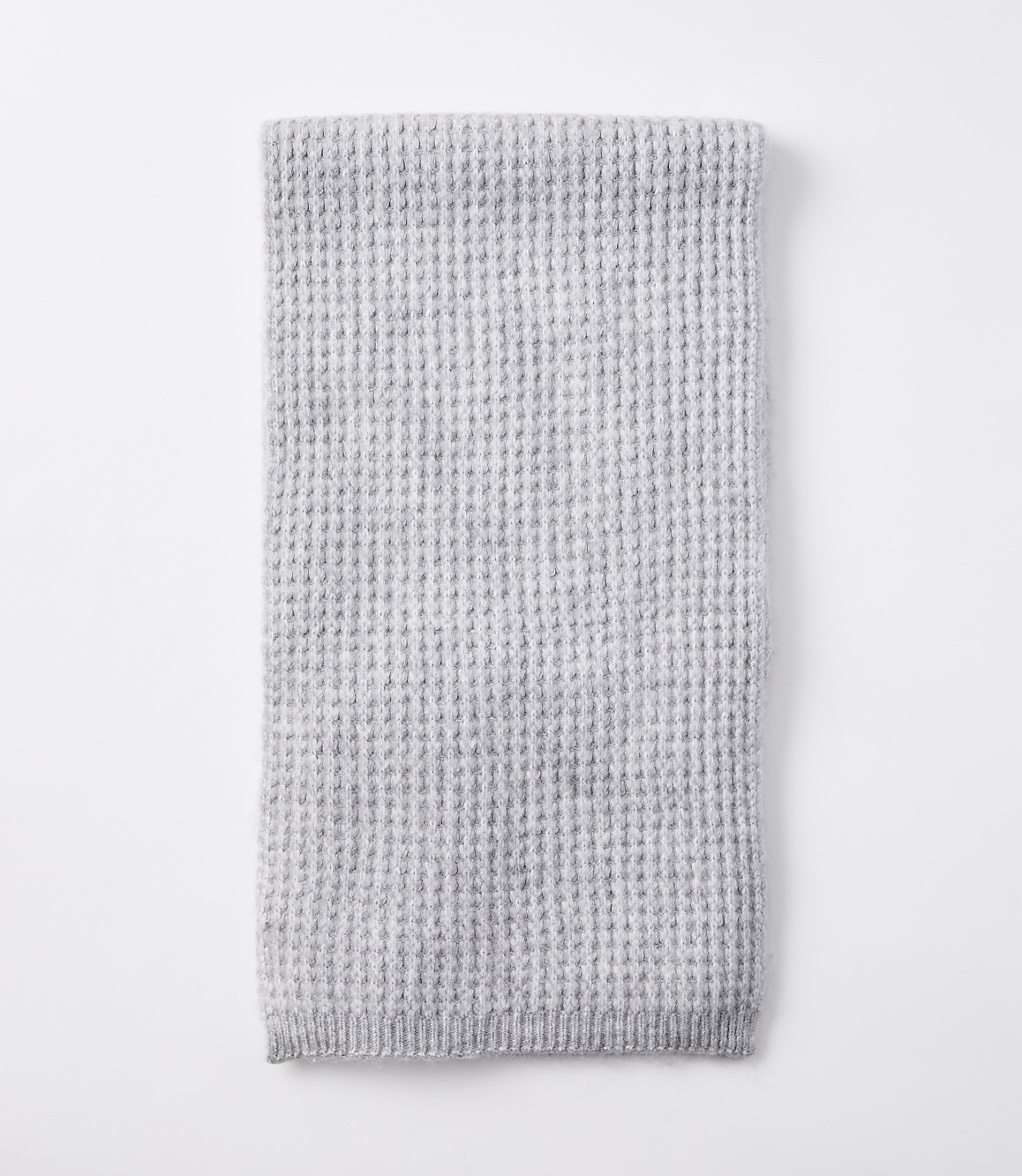 A folded light gray waffle-knit blanket rests on a plain white background.