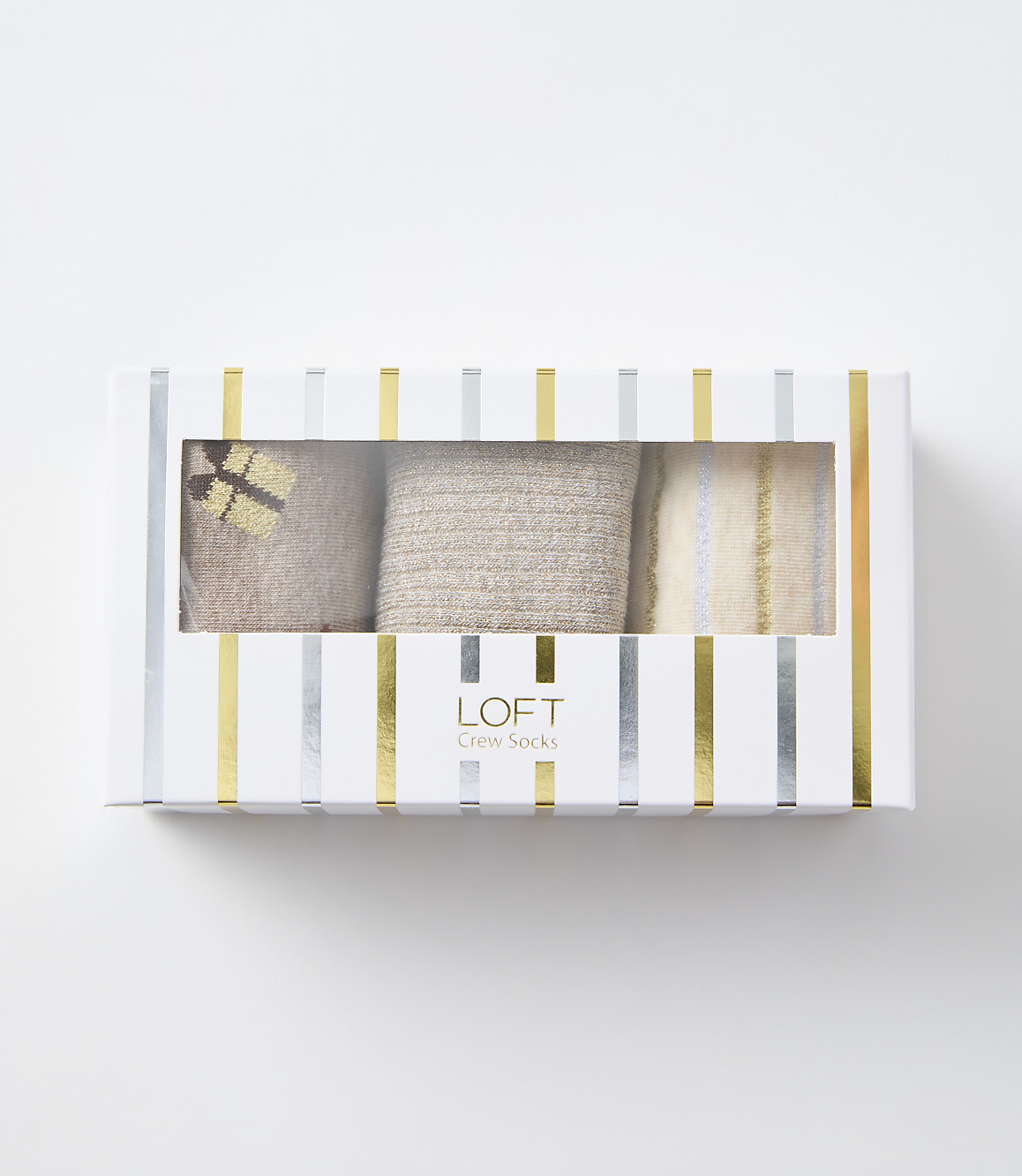 A white gift box with silver and gold stripes contains three pairs of cozy-looking crew socks, with a white background.