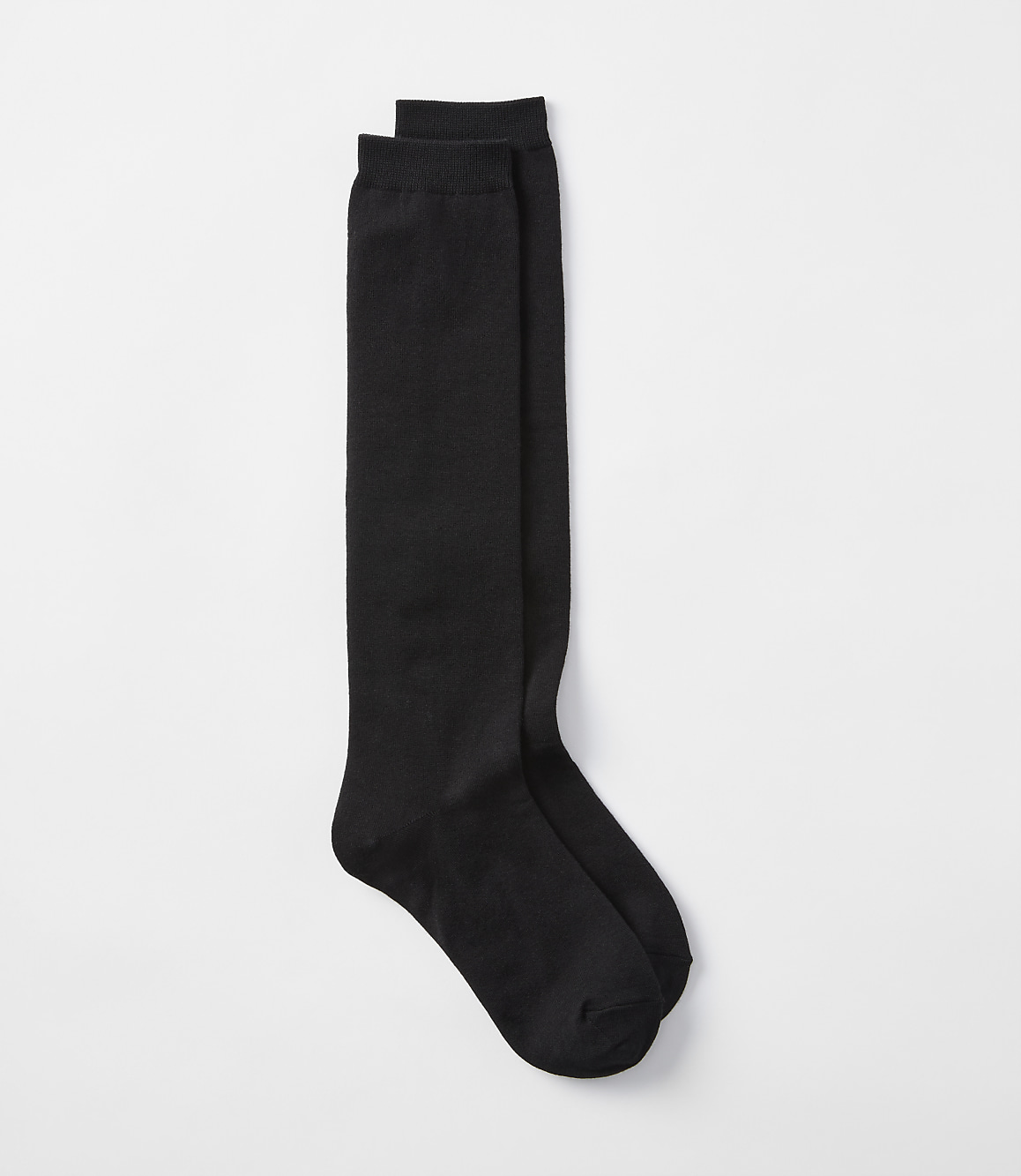 A pair of black knee-high socks lies on a plain white background.