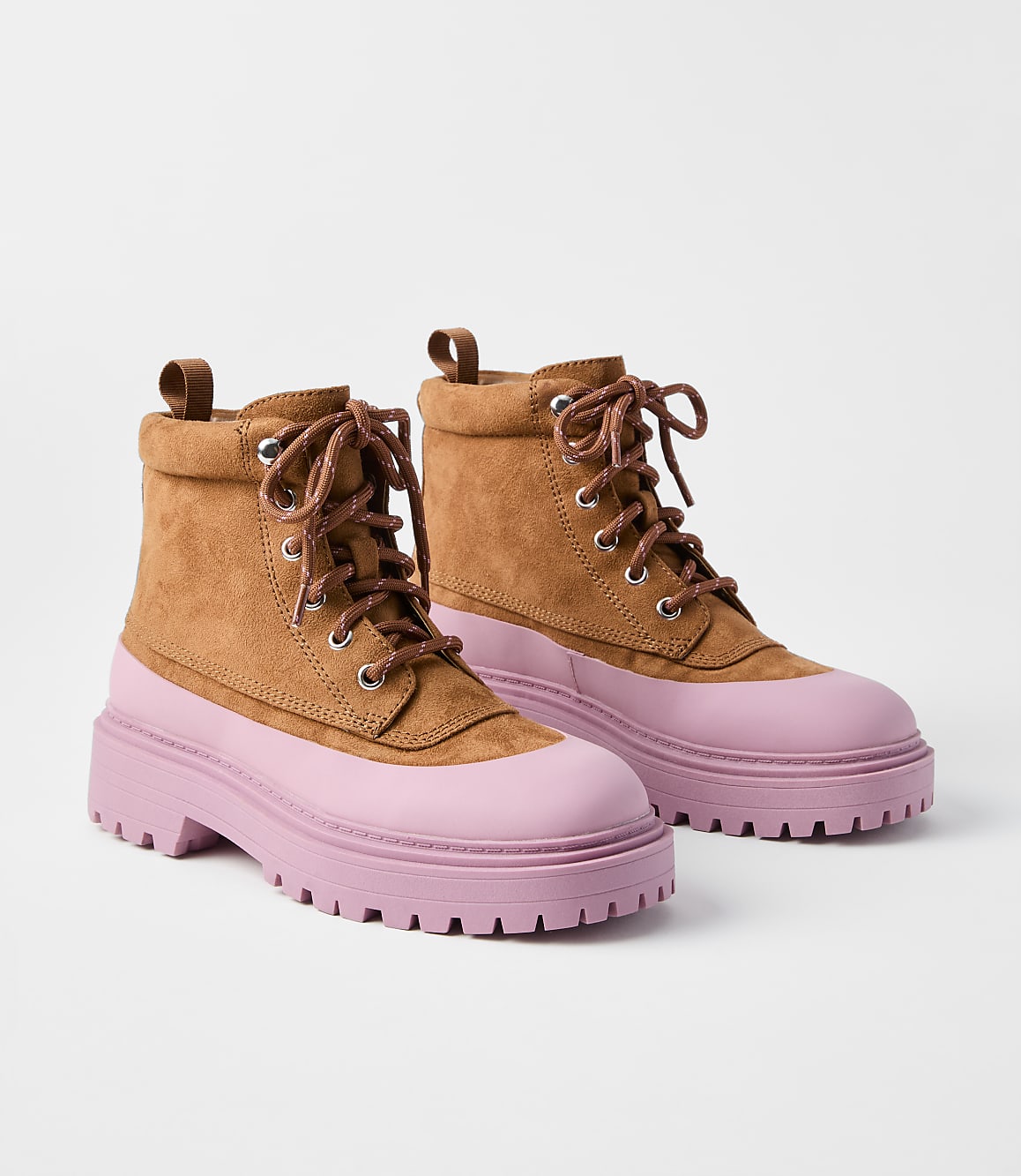 A pair of tan suede combat boots with pink rubber soles and toe caps are displayed against a plain white background.