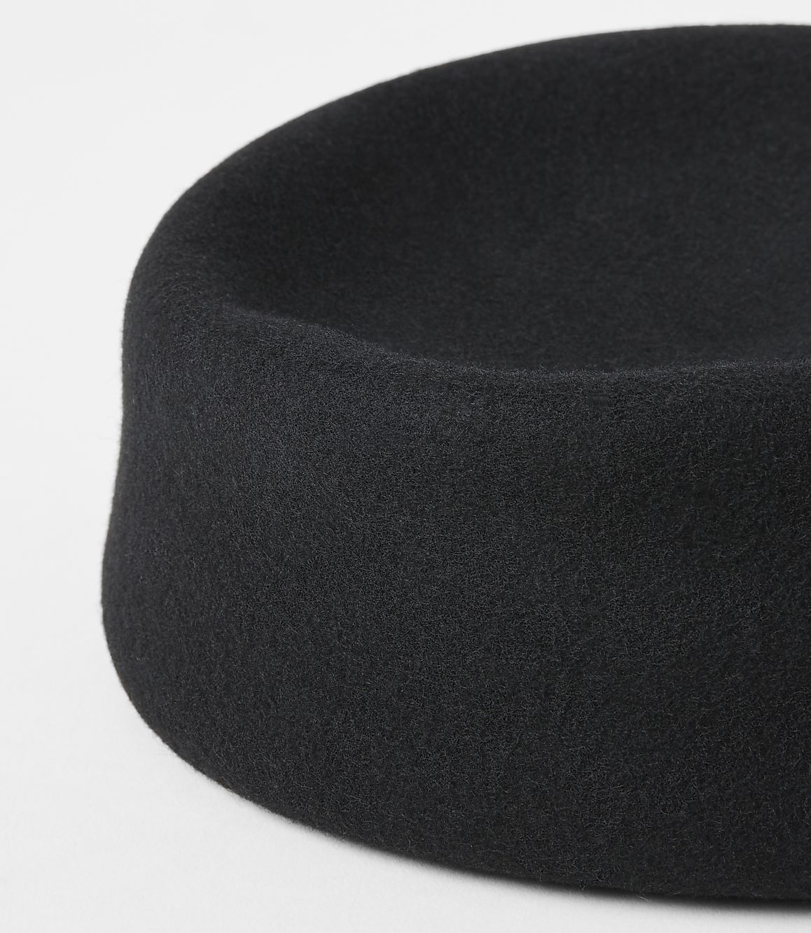 A black felt hat with a rounded crown sits on a plain white background.