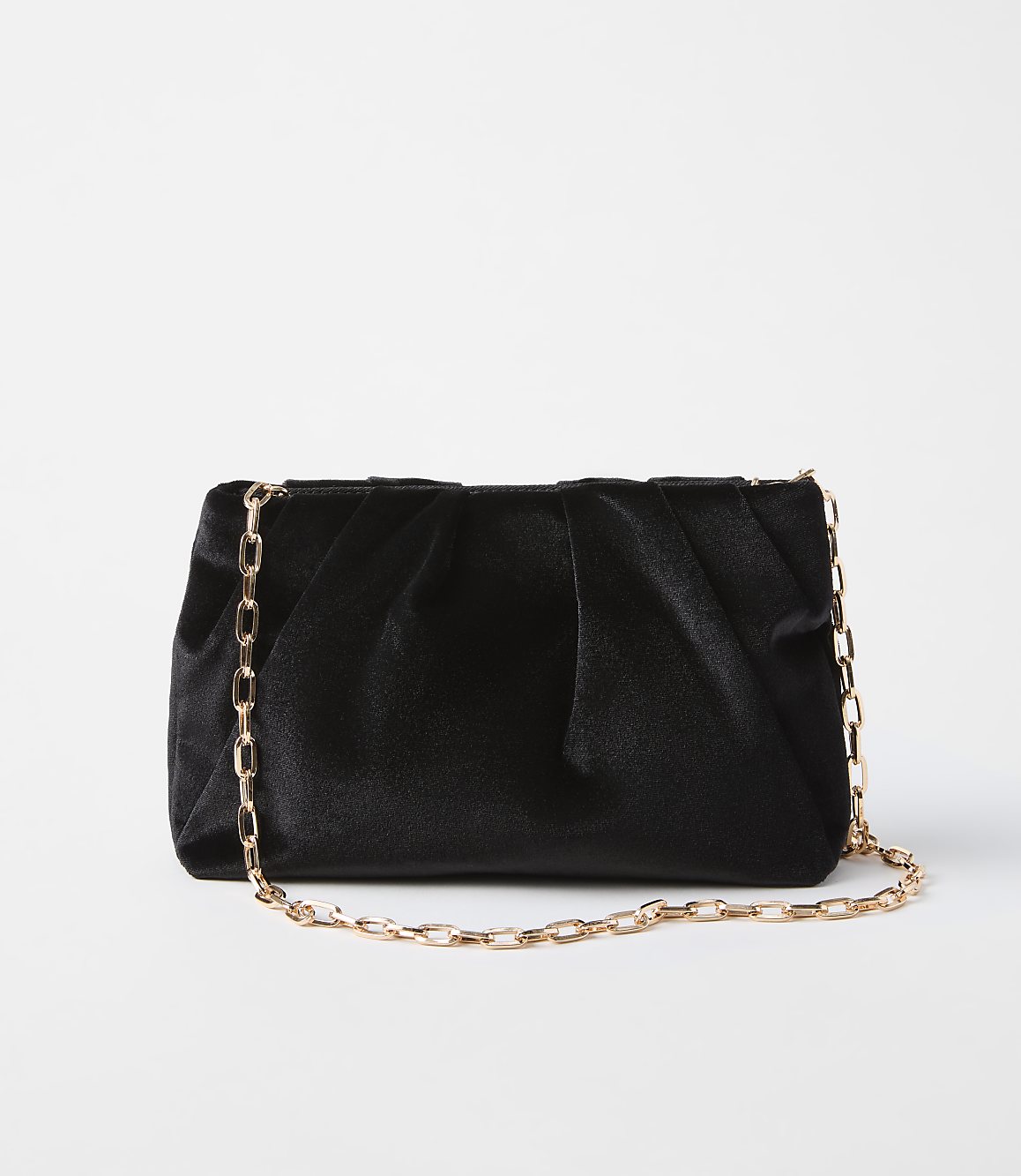 A black velvet clutch with a gold chain strap rests on a plain white background.