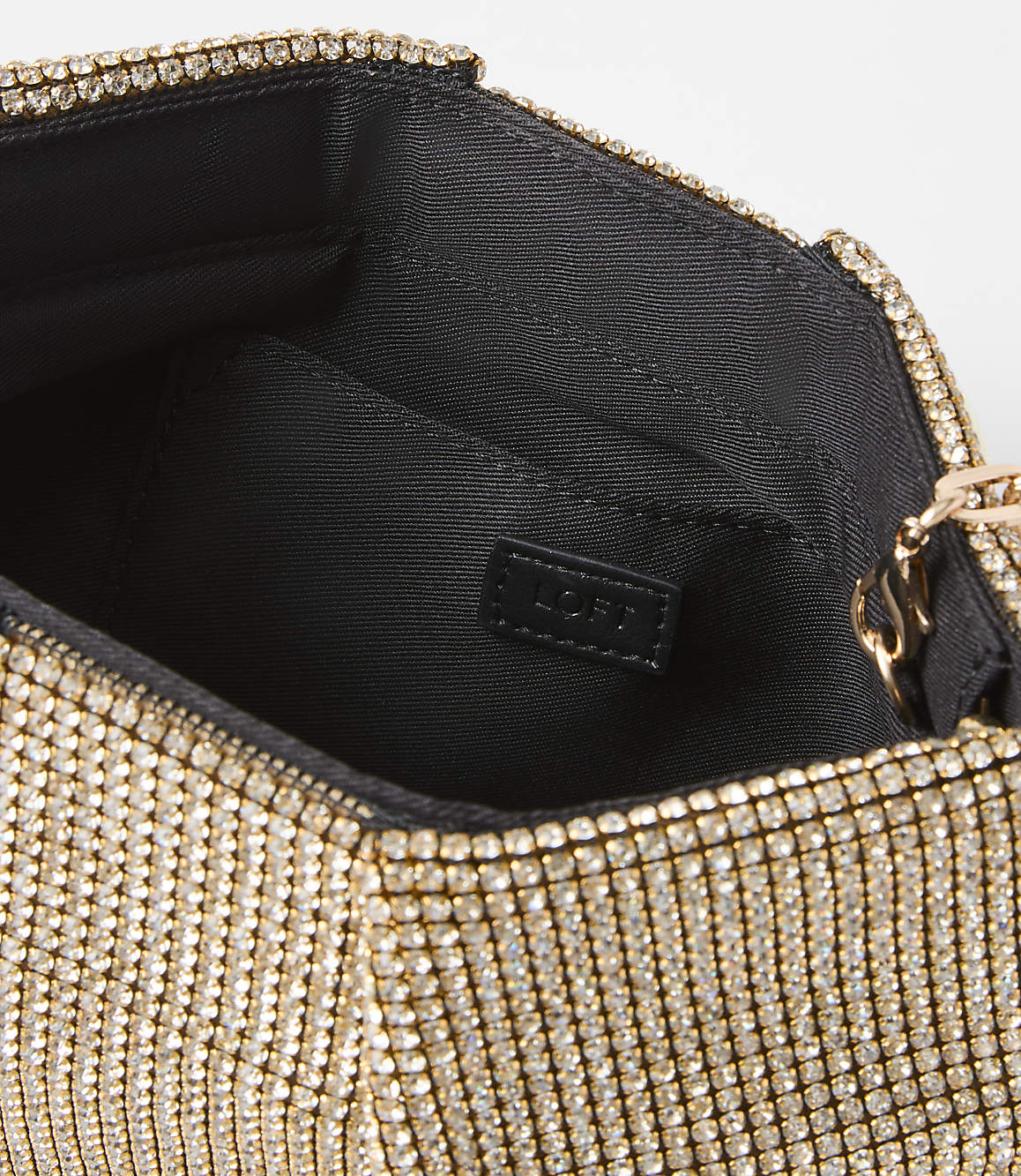 A sparkling gold clutch with a black interior is set against a plain white background.