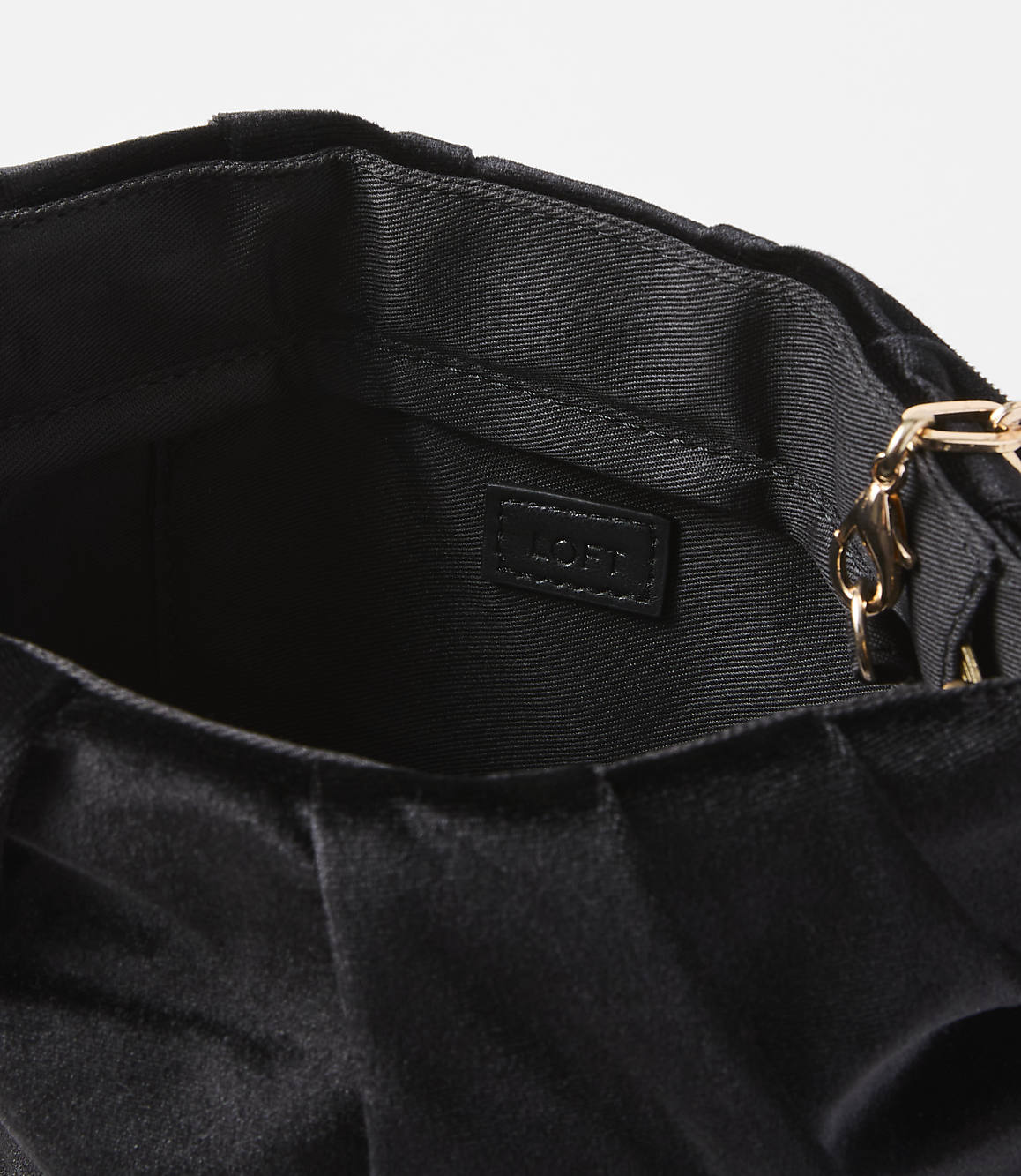 A black velvet clutch with a gold chain strap is shown against a plain white background.